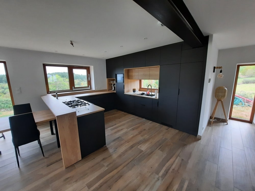 Vue d'ensemble d'une cuisine sur mesure noire et bois clair, conçue et posée à Montbrison par Chambon Maisse.